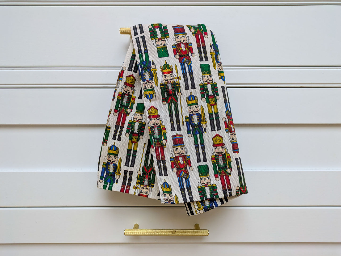 Nutcracker kitchen towel shown hanging on an inframe White kitchen with fashionable gold handles