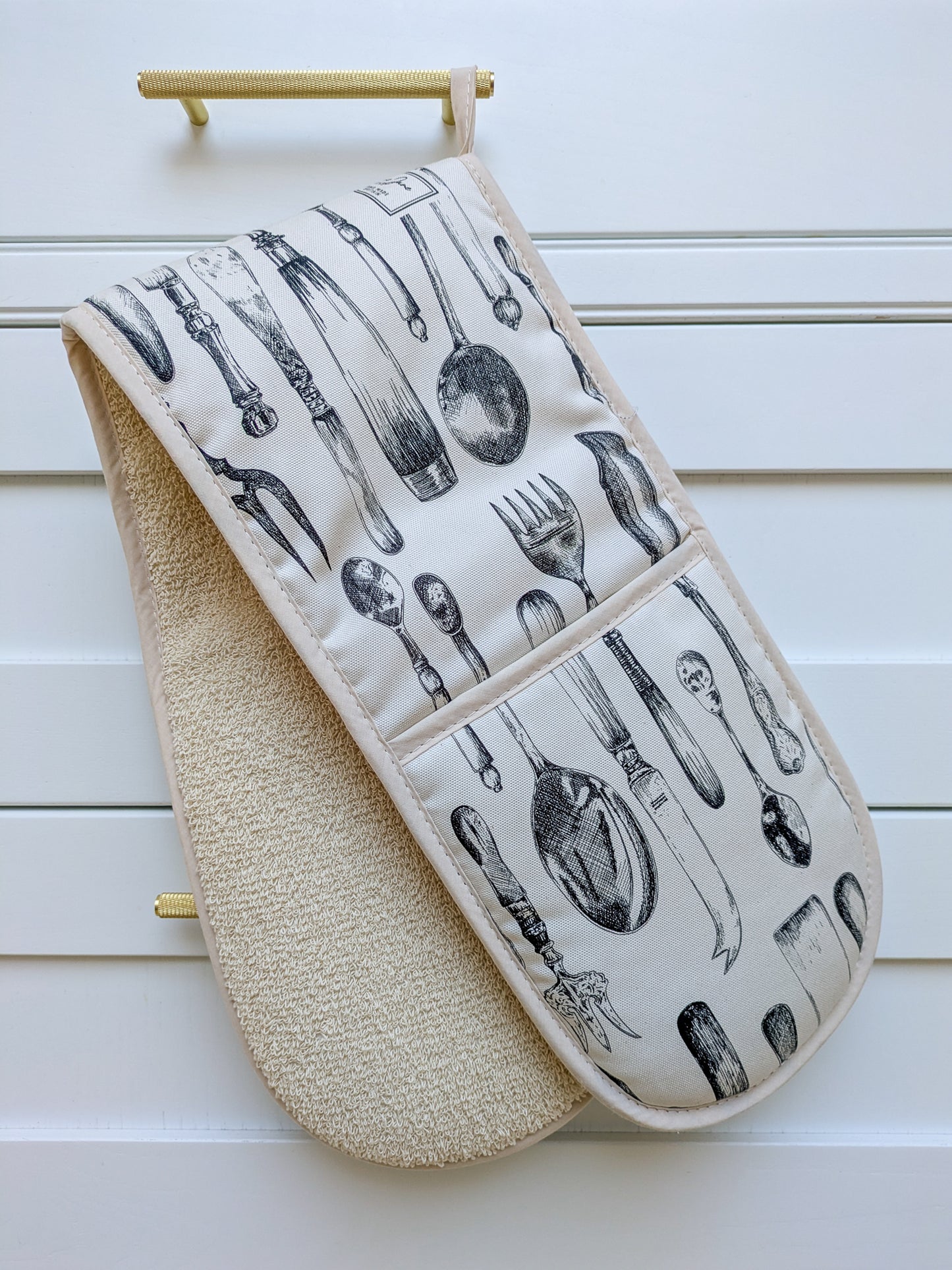 Cutlery patterned oven gloves hanging on a white in frame DIY kitchens pan drawer with knarled gold handles
