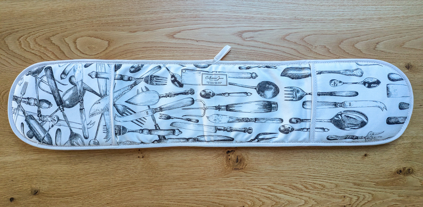 Overview of cutlery oven gloves showing the full design on a warm oak tabletop