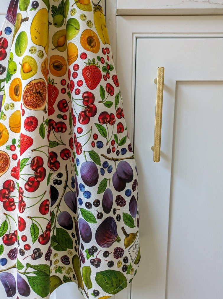 Rainbow colourful fruit illustrated tea towel hanging in beautiful warm white kitchen