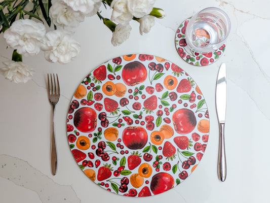 Red and orange fruit illustrated placemat and coaster on a crisp marble worktop with White freshly cut flowers