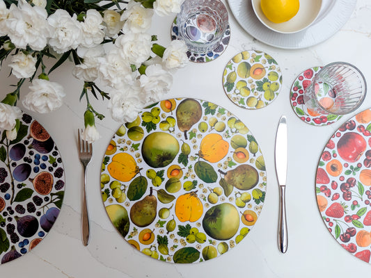 Green and yellow british fruit illustrated placemat and coaster set with mixed colourways on the table and spring flowers