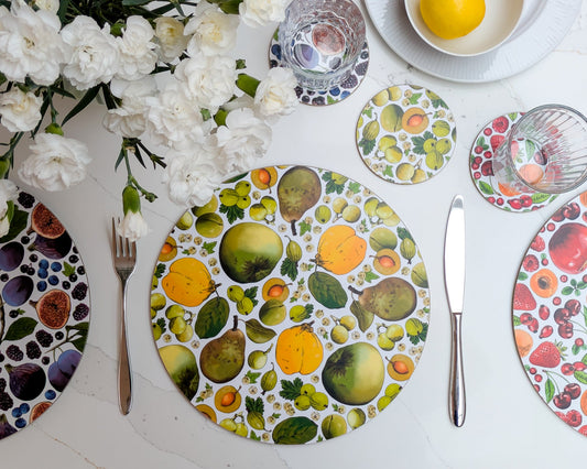 Green and yellow british fruit illustrated placemat and coaster set with mixed colourways on the table and spring flowers