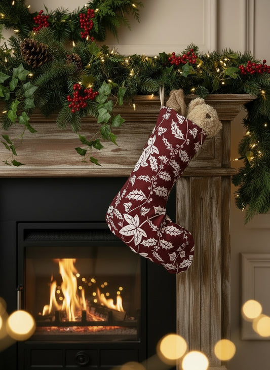 Red Christmas stocking with white holly pattern hanging on a lit fire with panelling and twinking lights