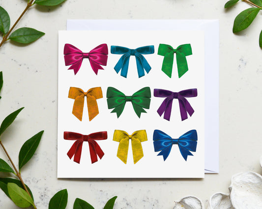 Bold and bright rainbow ribbon card pictured on a marble top with fresh foliage