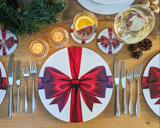 Warm tablesetting with red ribbon placemats and coasters and lit candles