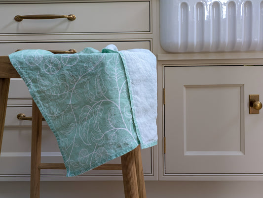 Tomato patterned towel draped over a wooden stool in a crisp country kitchen setting