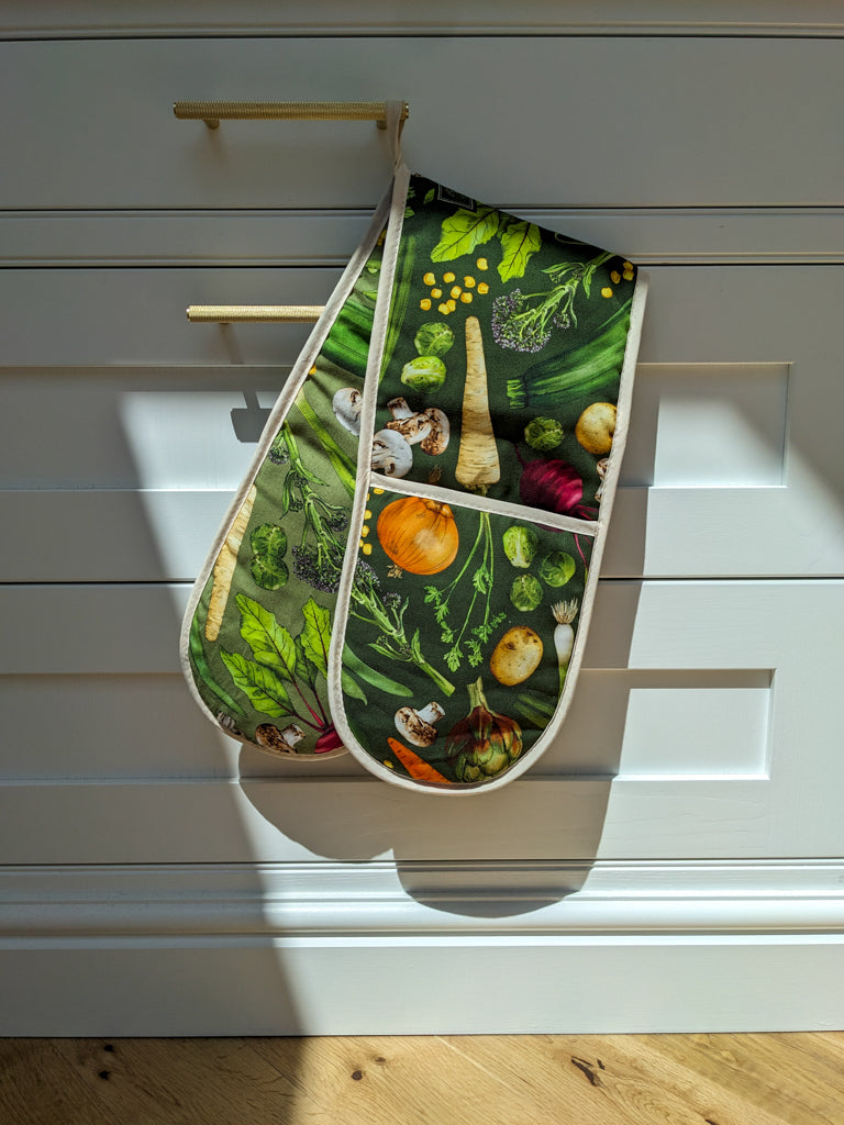 heat resistant cotton oven gloves, colourful design hanging on a crisp white in-frame kitchen with natural oak flooring, kitchen design idea