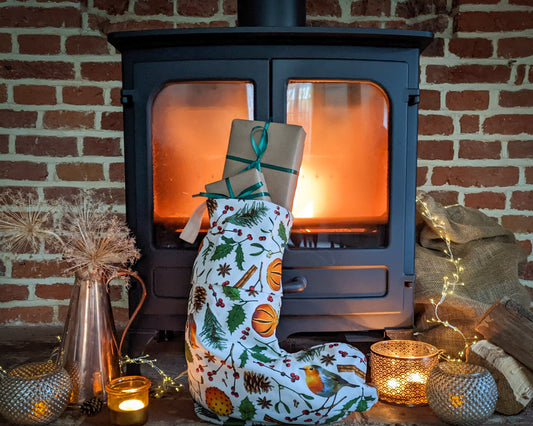 Christmas elements stocking full of gifts. Stocking pattern includes robins, holly, fir cones, berries, mistletoe and spiced oranges on a natural cotton background