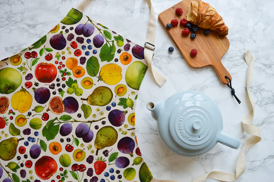 Fruit apron, natural background with warm tea and fresh croissant. Illustrated kitchen textiles