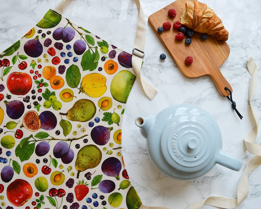 Fruit apron, natural background with warm tea and fresh croissant. Illustrated kitchen textiles