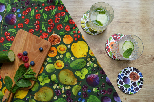 Colourful kitchen textiles. Red, Orange, Yellow, Green, Purple tea towel with fruit themed coasters and drinks