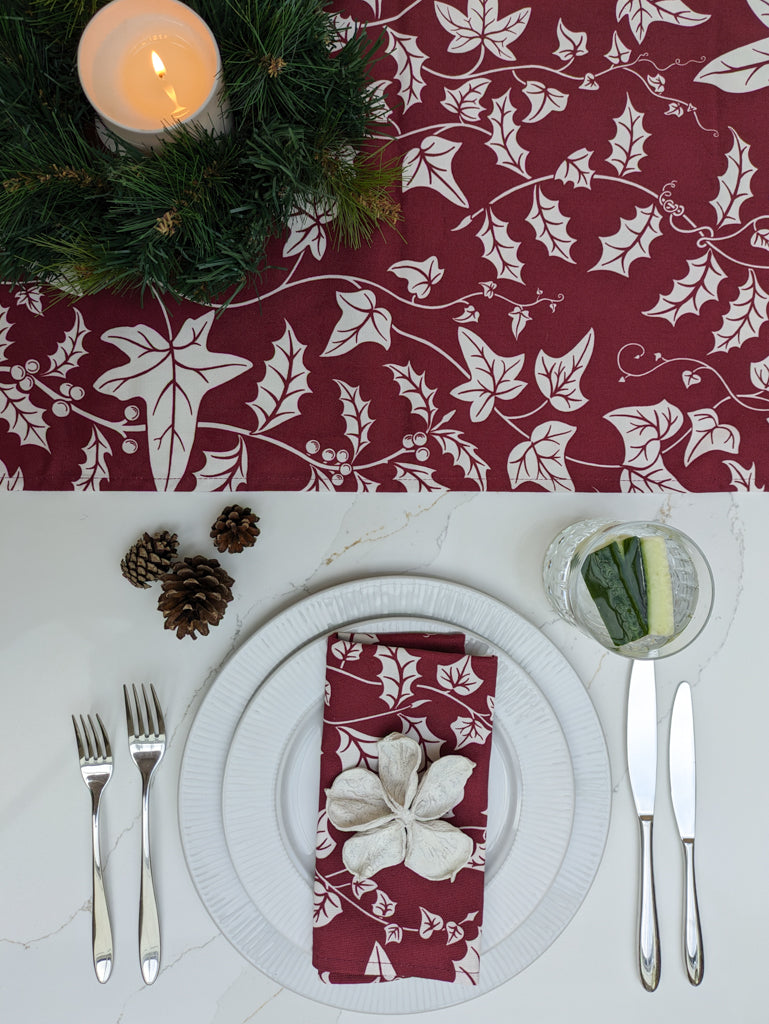 Crisp White and Burgundy festive table setting with botanical foliage illustrated table runner and napkin and festive props