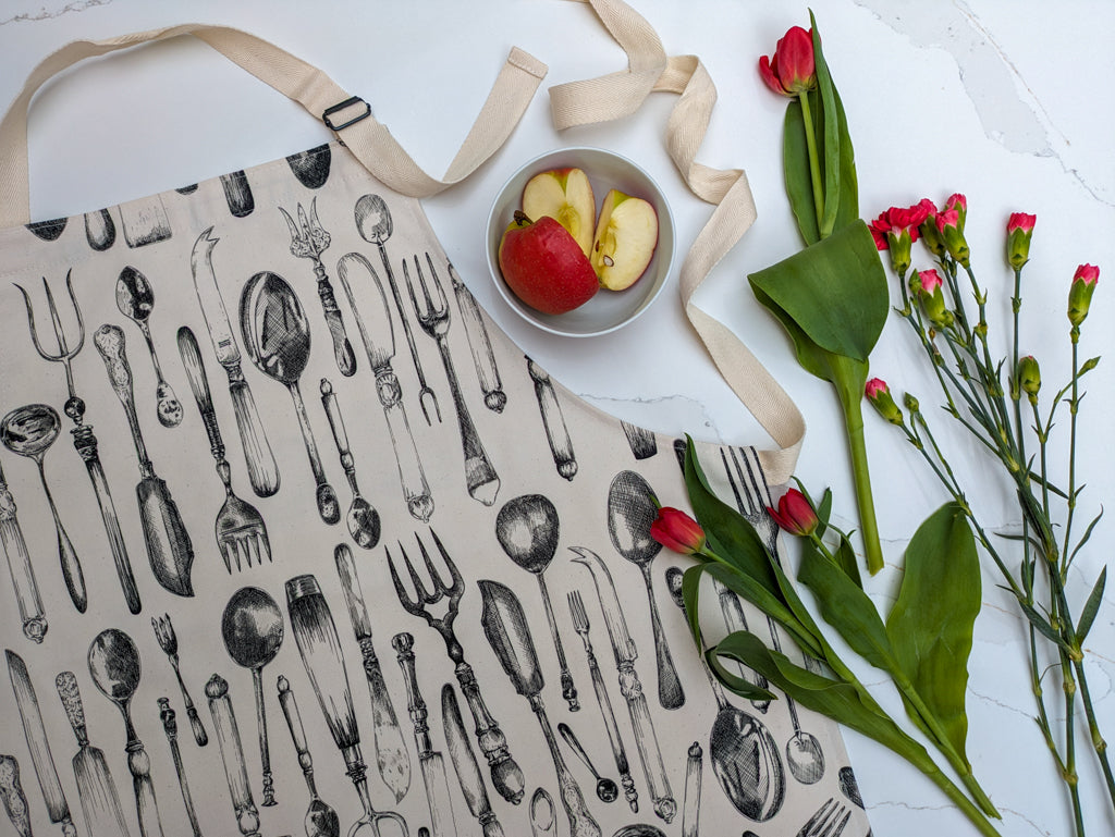 Detailed vintage cultery drawn apron with fresh cut flowers and apple