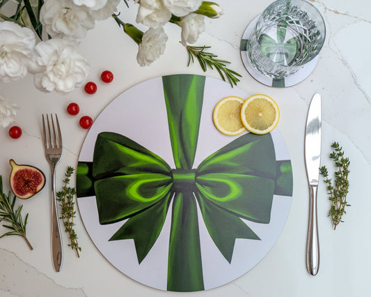 Round placemat with green bow design on a table setting with flowers and cutlery.