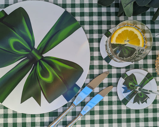 Table setting with green bow, cutlery, and decorative items on a gingham table cloth