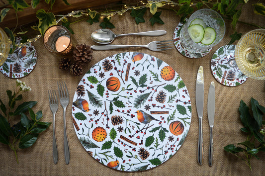 Christmas table setting, Christmas placemat with robins, holly, fir cones, berries, spiced oranges and cinnamon 