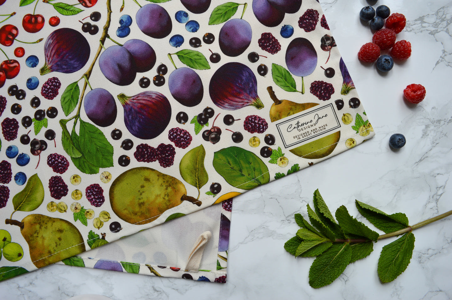 Close up of detailed illustrated rainbow coloured fruit tea towel