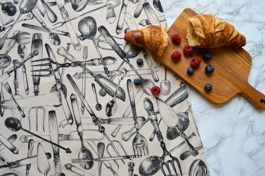 Cutlery drawings on a tea towel with fresh croissant and berries on marble top
